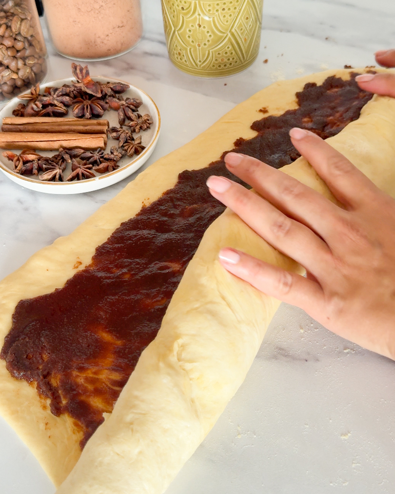 hands rolling cinnamon roll dough