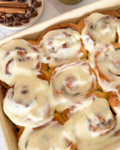 Baked cinnamon rolls in baking dish, topped with cream cheese icing