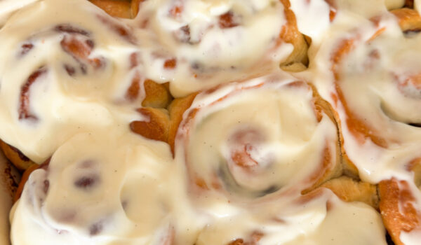Baked cinnamon rolls in baking dish, topped with cream cheese icing